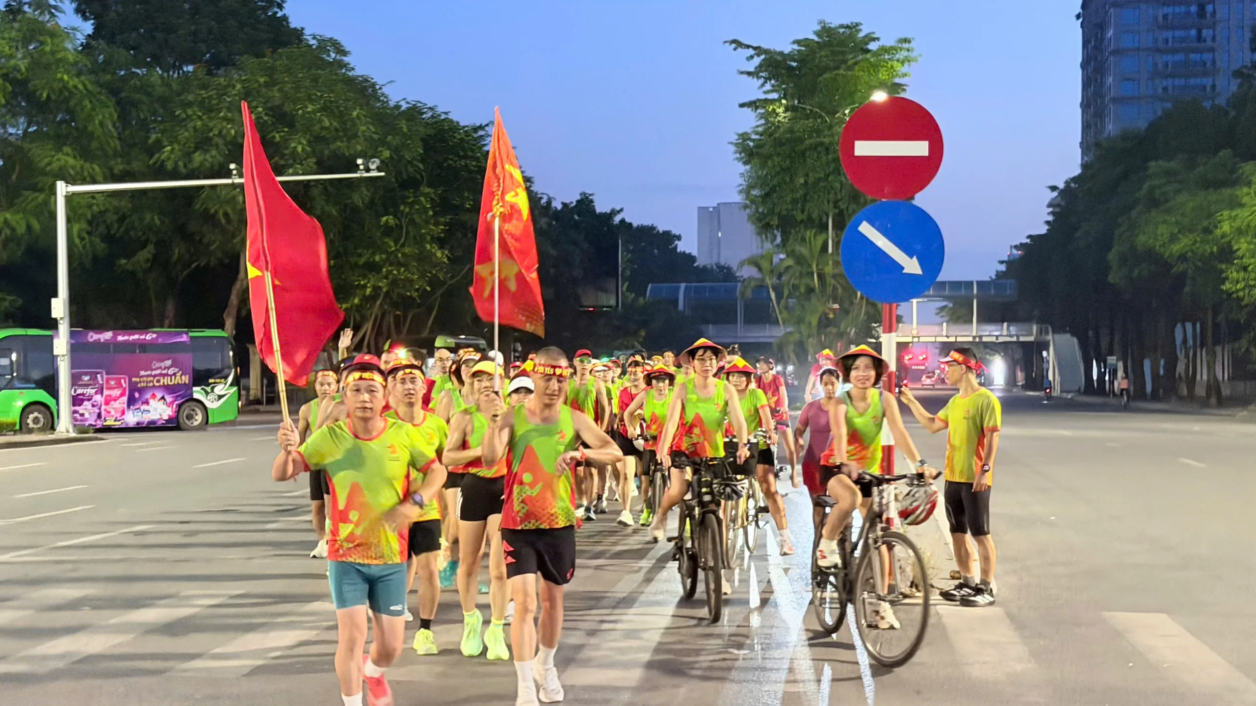 Đoàn Starlake chạy trên phố Hà Nội lúc trời còn nhá nhem, có xe đạp hộ tống và cờ Tổ quốc tung bay