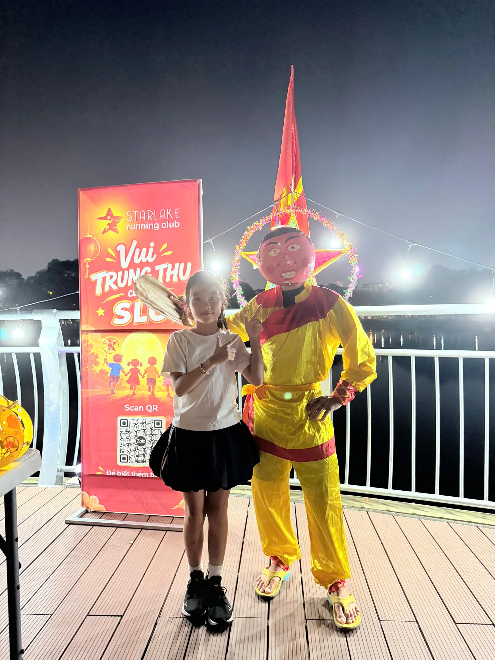Một bé gái Starlake tạo dáng cùng ông Địa trong đêm hội Trung Thu