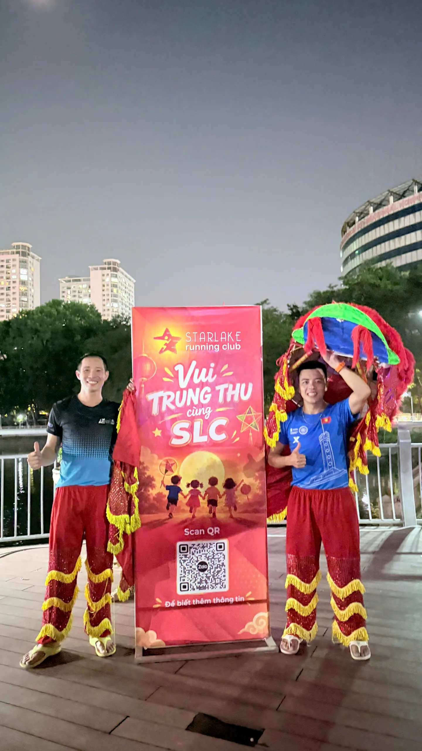 Hai thành viên Starlake hoá trang ông địa và lân tạo dáng bên banner Vui Trung Thu cùng SLC