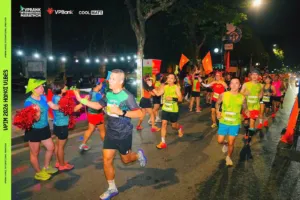 Một runner đập tay với đội cổ vũ giữa dòng người đang chạy qua trạm trong đêm