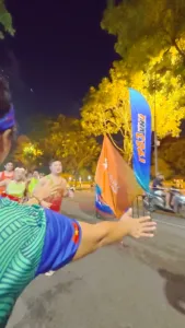 Cánh tay chìa ra đập tay các runner chạy ngang qua, bên cạnh là cờ cam Starlake và cờ hiệu 1983VNR